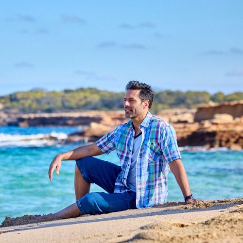 ein mann tragt ein kariertes hemd und entspannt sich am strand