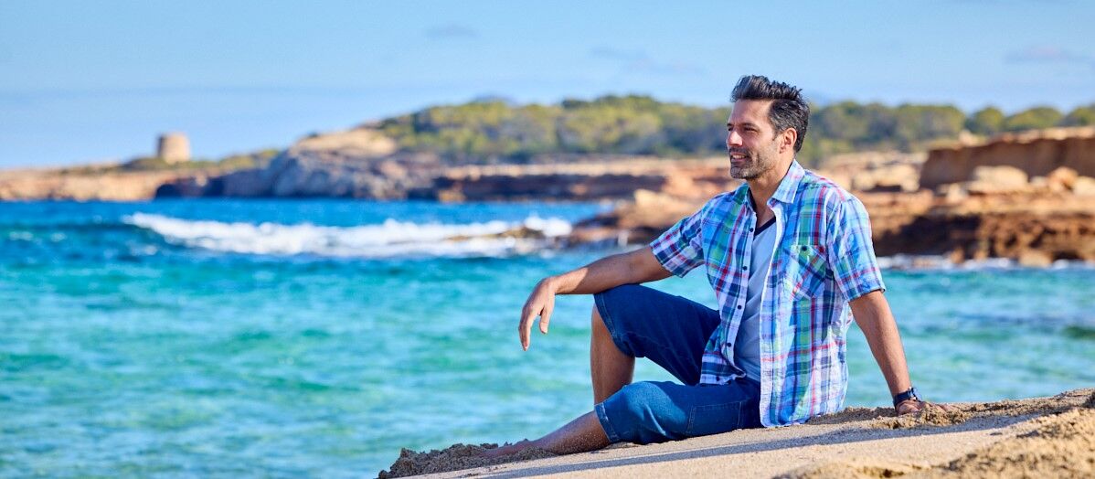 ein mann tragt ein kariertes sommerhemd und entspannt sich am strand