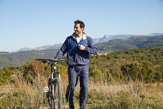 Muž v přírodě v teplákové soupravě s jízdním kole